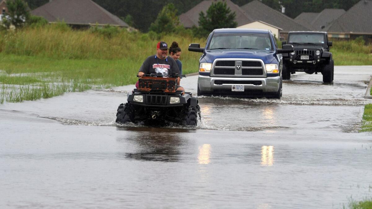 Jason Hendry drives his daughter, Callie, out of their neighborhood on a flooded road in Lumberton, Texas, on Aug. 27, 2017.