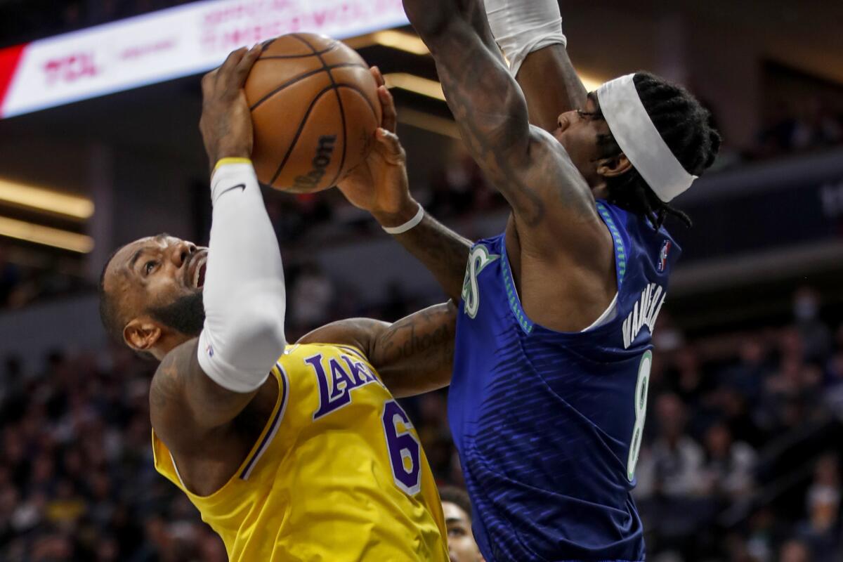 The Lakers' LeBron James, left, is fouled by the Timberwolves ' Jarred Vanderbilt in the first quarter Dec. 17, 2021.
