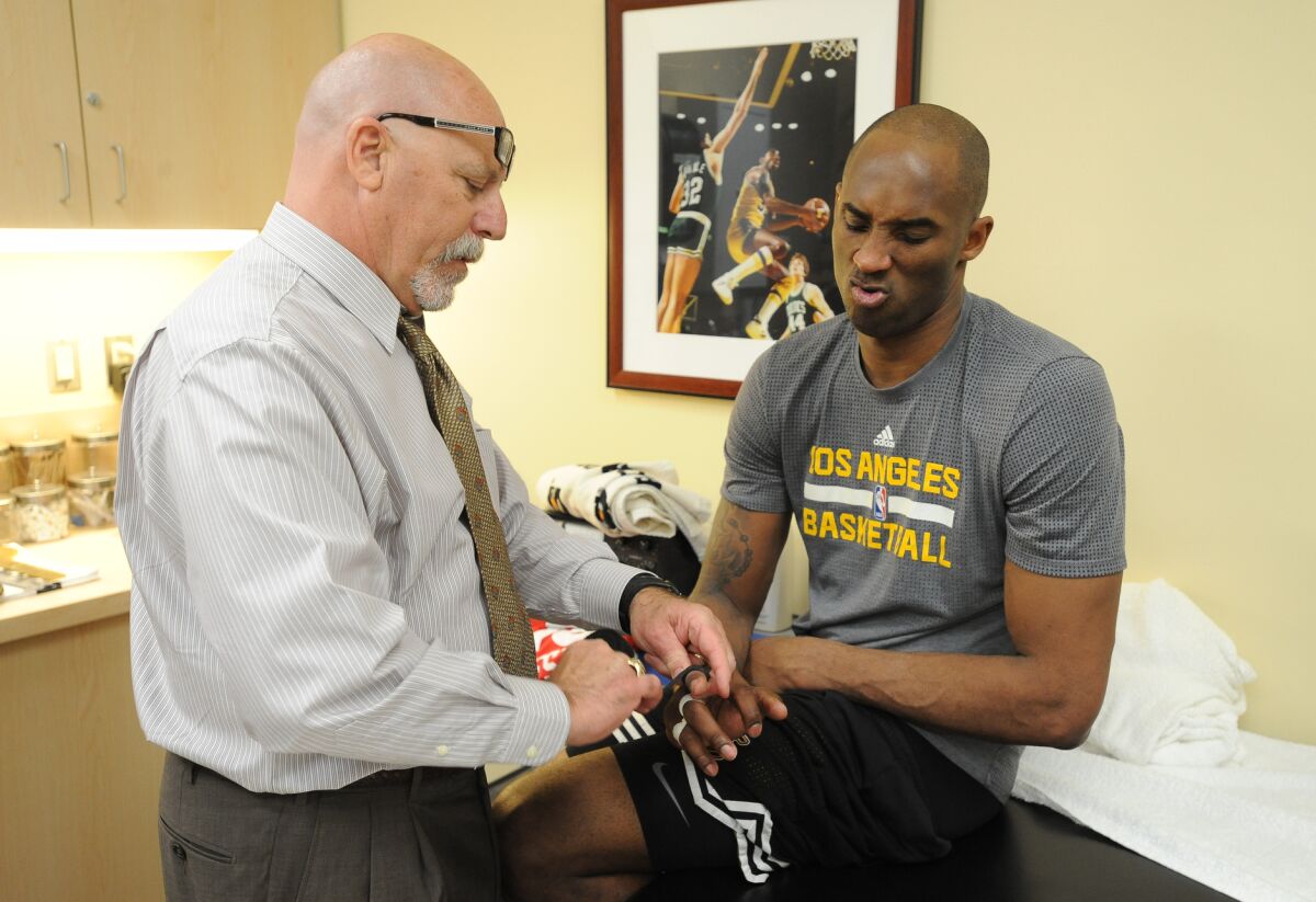Then-Lakers trainer Gary Vitti tapes one of Kobe Bryant's fingers Feb. 19, 2016, at Staples Center.