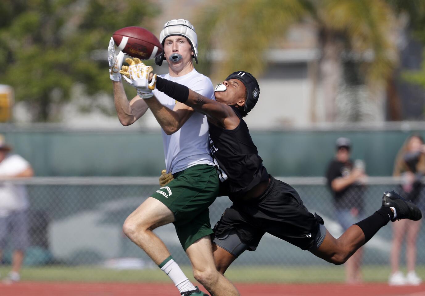 Edison High's Ryan Rivituso, left, completes a pass by quarterback Jacob Hanlon (not pictured) against Servite in pool play during the Battle at the Beach passing tournament at Edison High on Saturday.