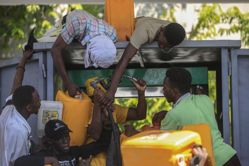FILE - People wrangle over a gas pump as they try to get their tanks filled at a gas station, in Port-au-Prince, Haiti, Nov 4, 2021. The U.S. government is urging U.S. citizens to leave Haiti given the country’s deepening insecurity and a severe lack of fuel that has affected hospitals, schools and banks. Gas stations remained closed on Thursday, Nov. 11, 2021, a day after the State Department issued its warning. (AP Photo/Odelyn Joseph, File)