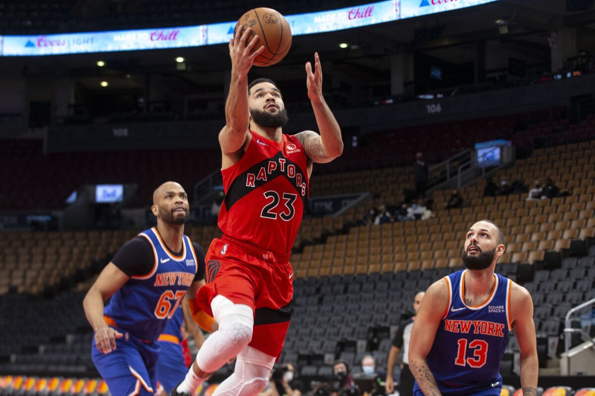 Toronto Raptors' Fred VanVleet, center, scores a basket as New York Knicks' Evan Fournier, right, and Taj Gibson look on during first-half NBA basketball game action in Toronto, Sunday, Jan. 2, 2022. (Chris Young/The Canadian Press via AP)