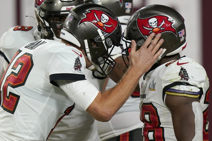 Tampa Bay Buccaneers quarterback Tom Brady puts his hand on running back Leonard Fournette's helmet.