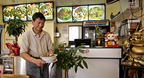 Ji Xian Liang prepares to serve a dish to customers at Happy Kitchen.