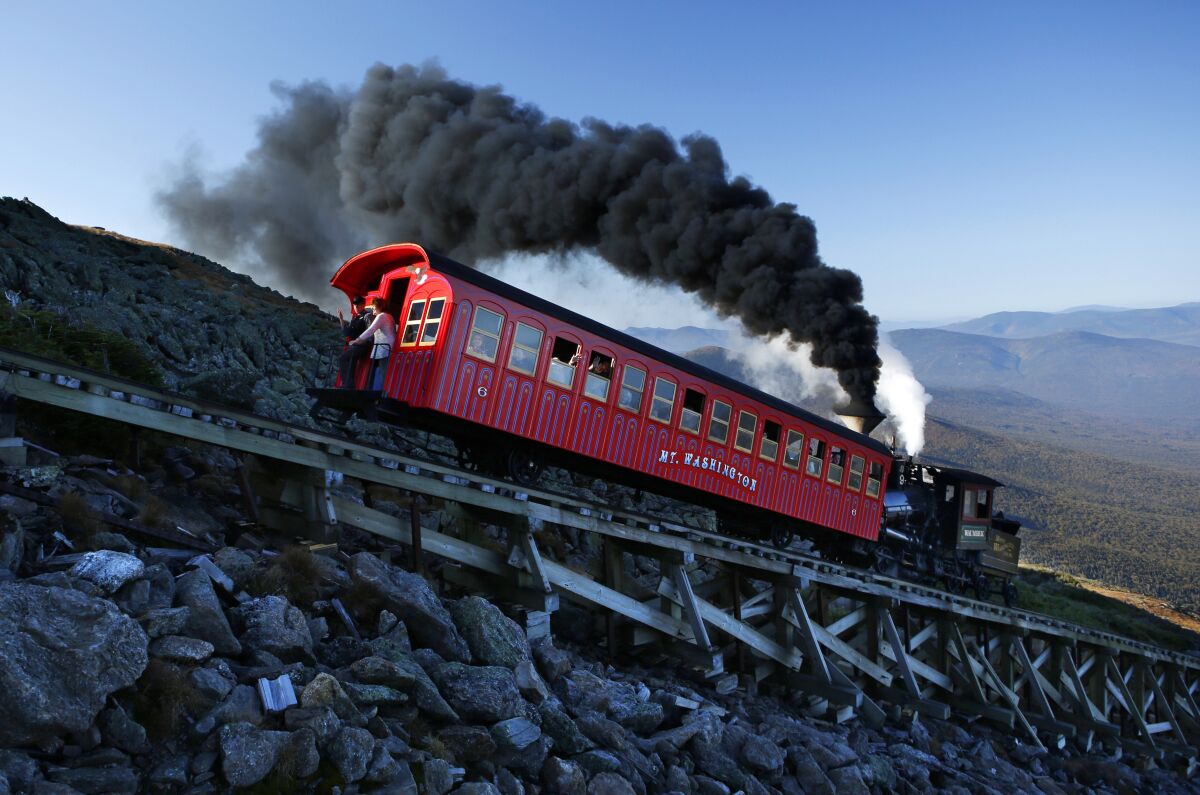 FILE- A vintage coal-fired steam engine pushes a passenger car up the Cog Railway on a 3.8-mile journey to the summit of 6,288-foot Mount Washington in New Hampshire, Sunday, Sept. 24, 2017. The owner of the railway is proposing accommodations and a restaurant near the summit of New Hampshire's highest peak. (AP Photo/Robert F. Bukaty, File)