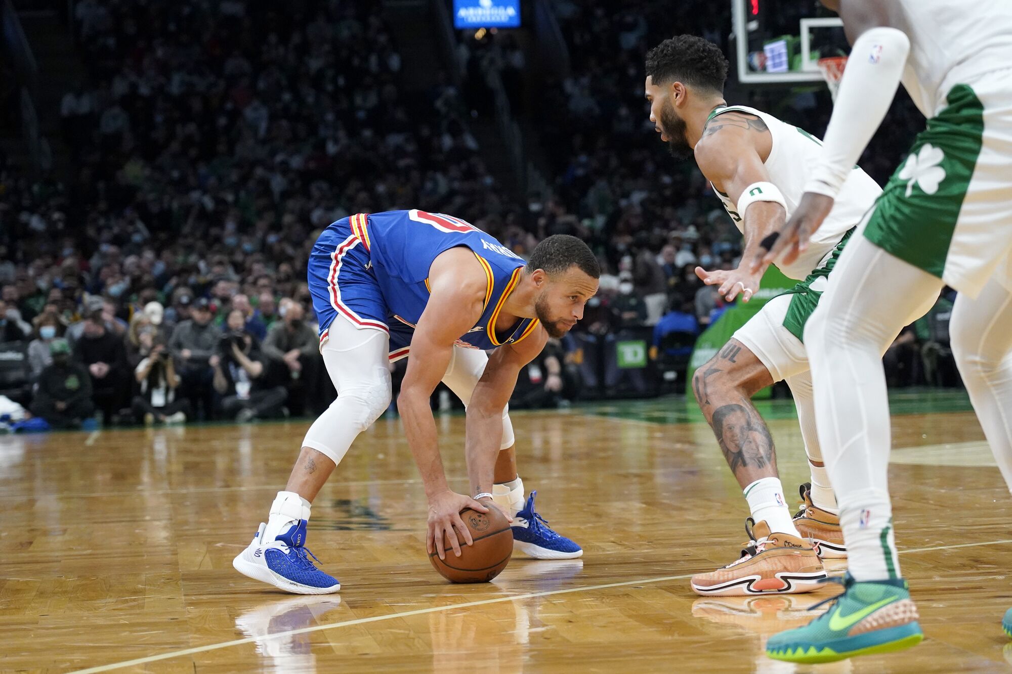 Warriors guard Stephen Curry puts the ball on the court as he sized up Celtics defender Jayson Tatum.