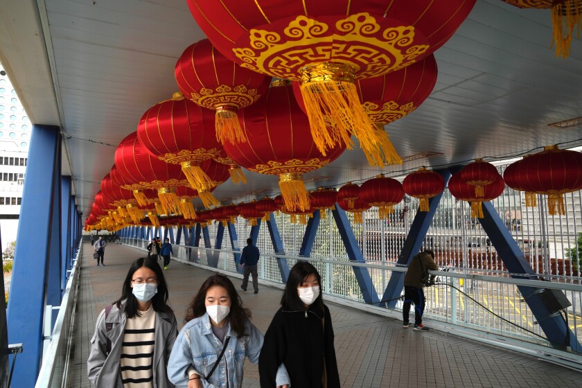 Gente con mascarillas pasa por un puente decorado por el Año Nuevo Lunar en Hong Kong, el lunes 18 de enero de 2022. (AP Foto/Kin Cheung)