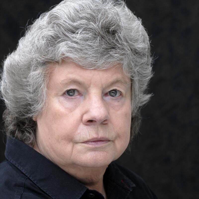 A closeup image of a woman with short gray hair looking directly at the camera