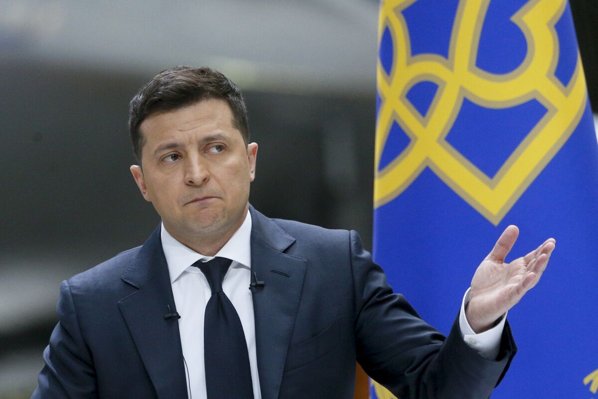 Ukrainian President Volodymyr Zelenskyy gestures while speaking to the media during a news conference with the world's largest airplane, Ukrainian Antonov An-225 Mriya in the background, at the Antonov aircraft factory in Kyiv, Ukraine, Thursday, May 20, 2021. (AP Photo/Efrem Lukatsky)