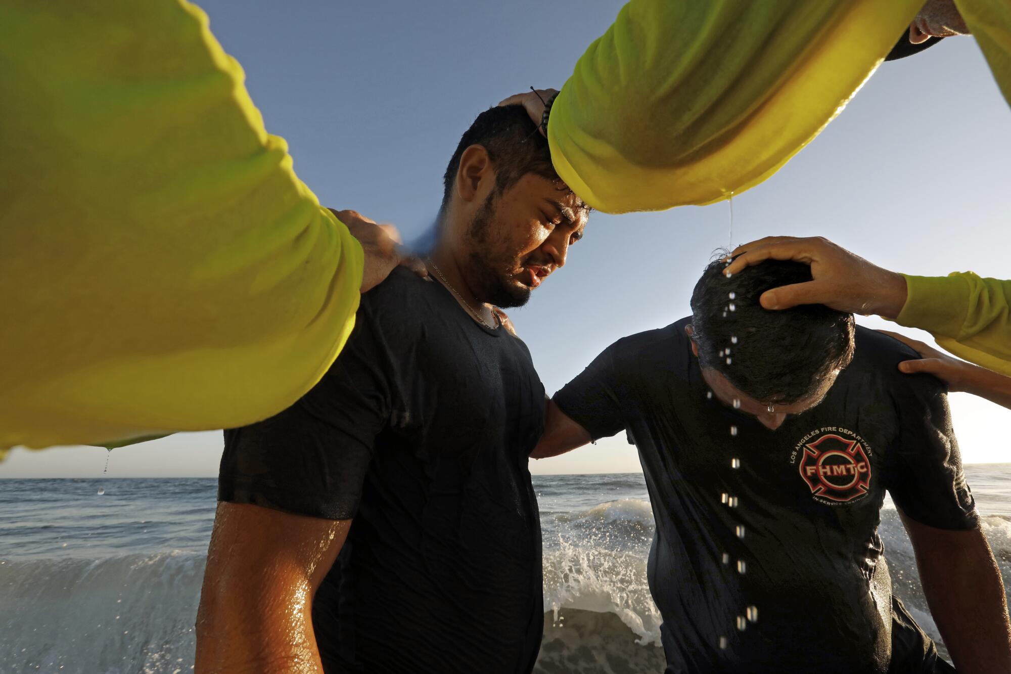 Two young men are baptized near 13th Street in Newport Beach by members of Saturate OC.