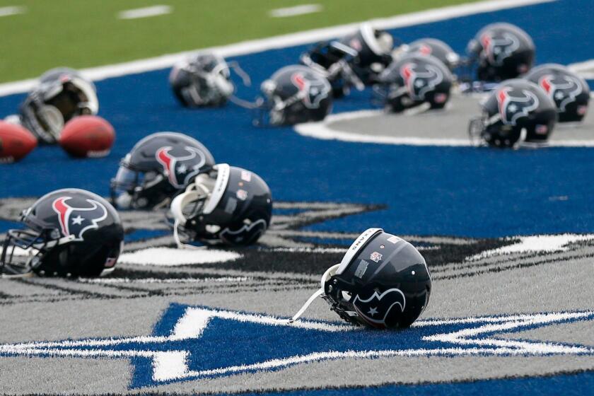 Several Houston Texans helmets sit over the Dallas Cowboys logo in the end zone as the Texans prepare for a morning work out at the Cowboys training facility, Monday, Aug. 28, 2017, in Frisco, Texas. The Texans are working out in the practice facility of the Cowboys because of floods pounding Houston. An exhibition game in the Texans' stadium Thursday might be moved to the home of the Cowboys.(AP Photo/Tony Gutierrez)