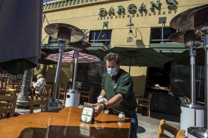 VENTURA, CA - MARCH 16: Dargan's owner Liam Sherlock cleans table outside his pub on Main St. Tuesday, March 16, 2021 in Ventura, CA. (Brian van der Brug / Los Angeles Times)