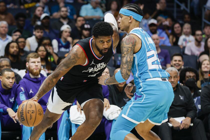 Los Angeles Clippers forward Paul George, left, drives into Charlotte Hornets guard Tre Mann.