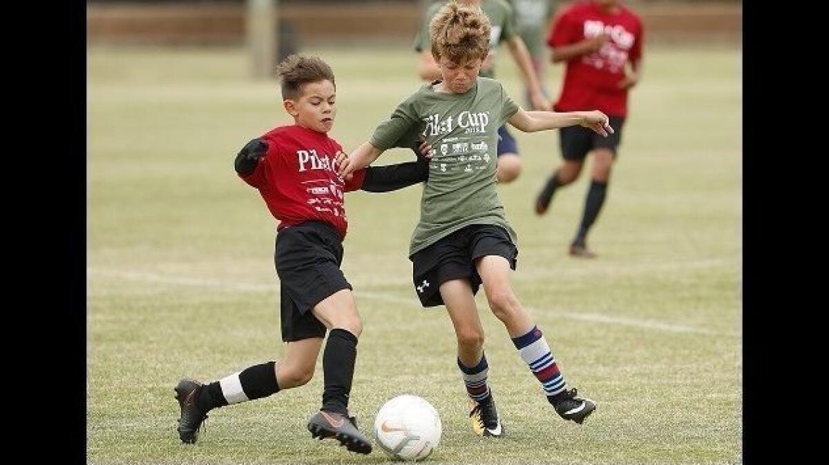 Chris Esparza, left, battles for the ball against Tate Oyler during a boys' sixth-grade gold division game Tuesday in the Daily Pilot Cup youth soccer tournament.