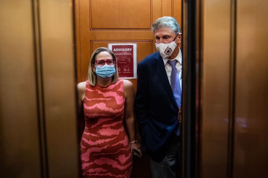 Sen. Kyrsten Sinema and Sen. Joe Manchin  catch and an elevator to go to the Senate Chamber to vote,