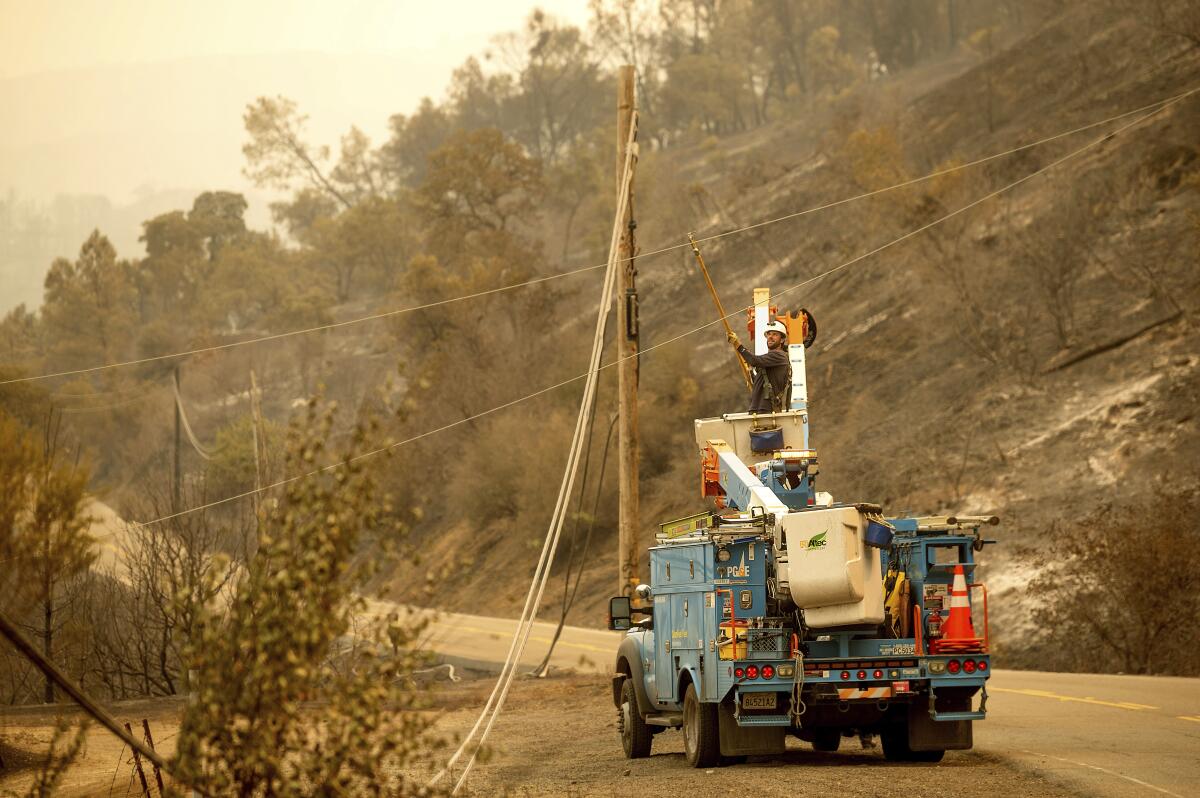 A Pacific Gas & Electric Co. worker clears a power line blocking a roadway in unincorporated Napa County on Aug. 20.