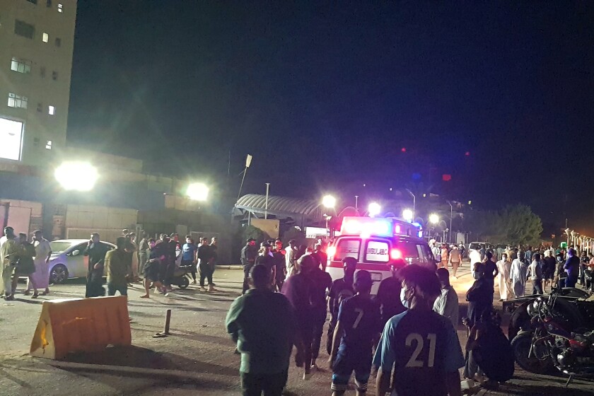 People gather outside a hospital at night.