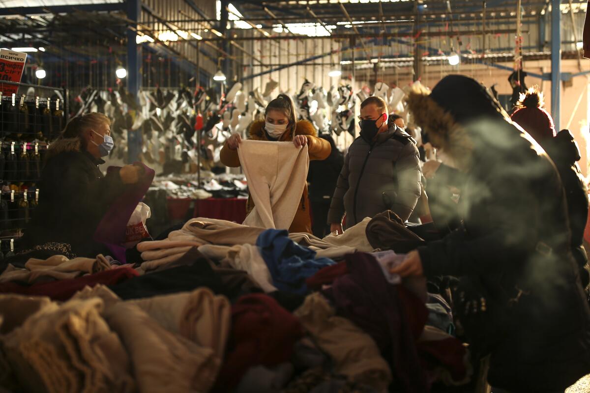 Shoppers in masks look through piles of fabric.