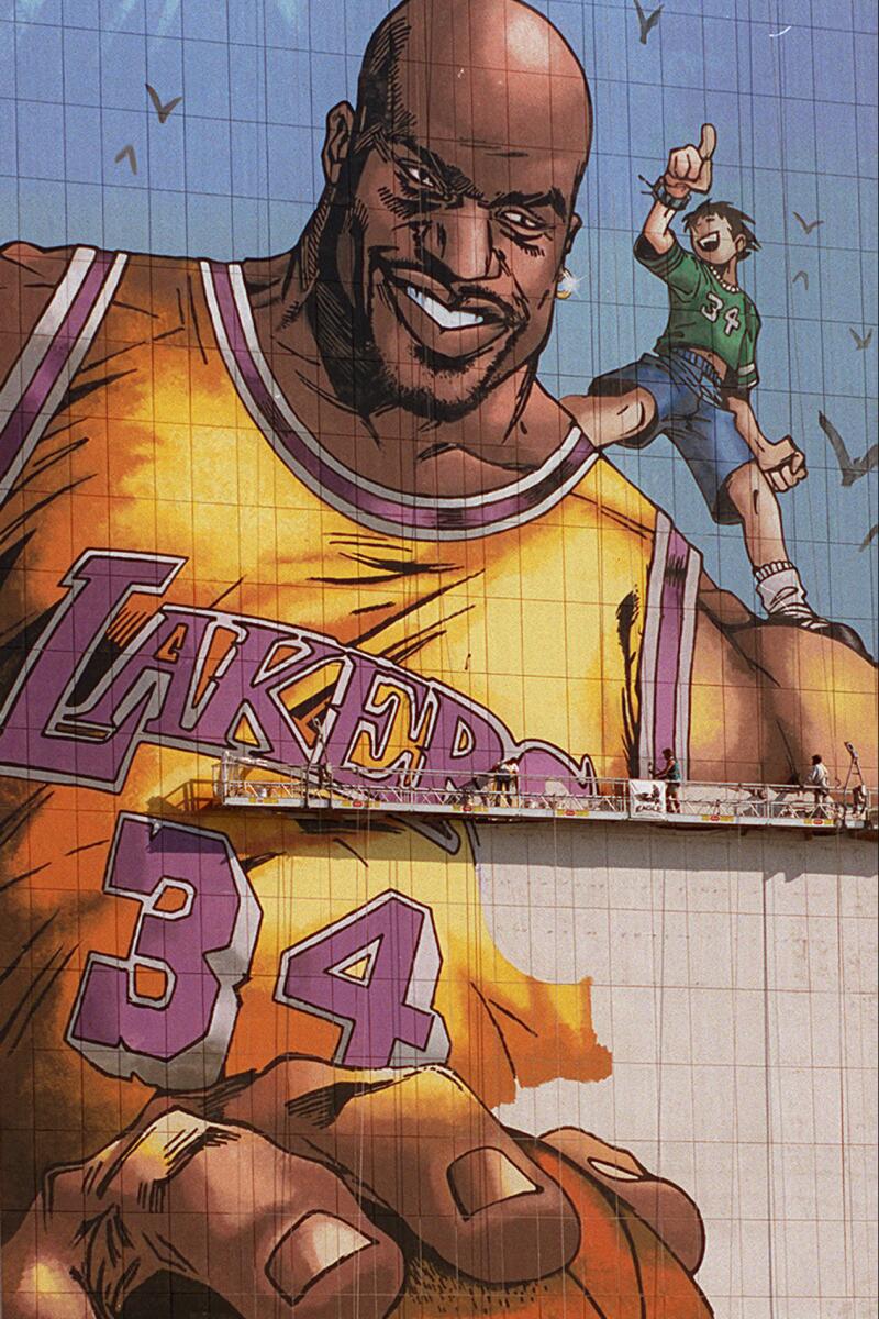 Artists are dwarfed by the image of new Laker Shaquille O'Neal on Nov. 18, 1996, on the side of a downtown Los Angeles building.