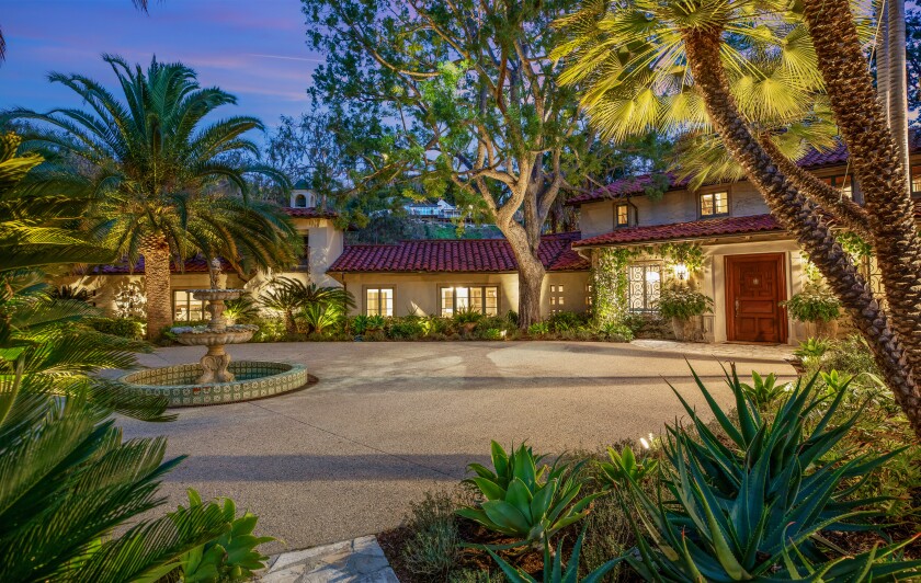 Trees surround a motorcourt in front of the Mediterranean-style villa .