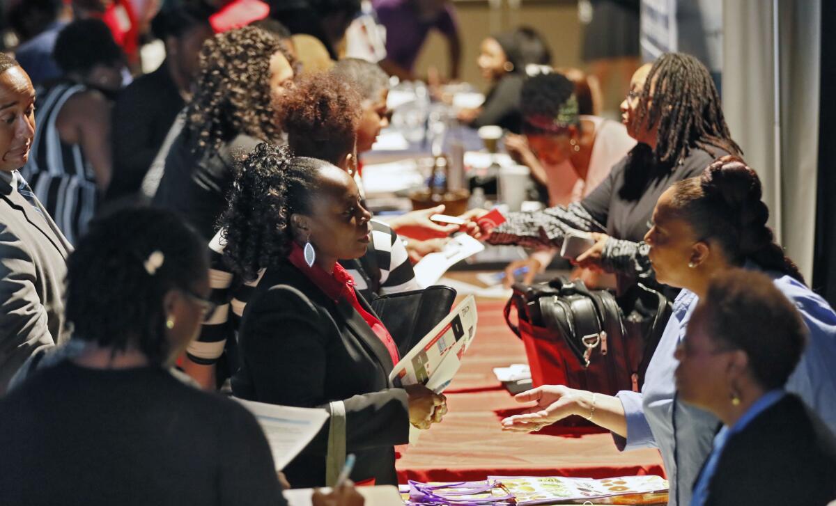 Company representatives talk with potential applicants at a job and resource fair in Atlanta.