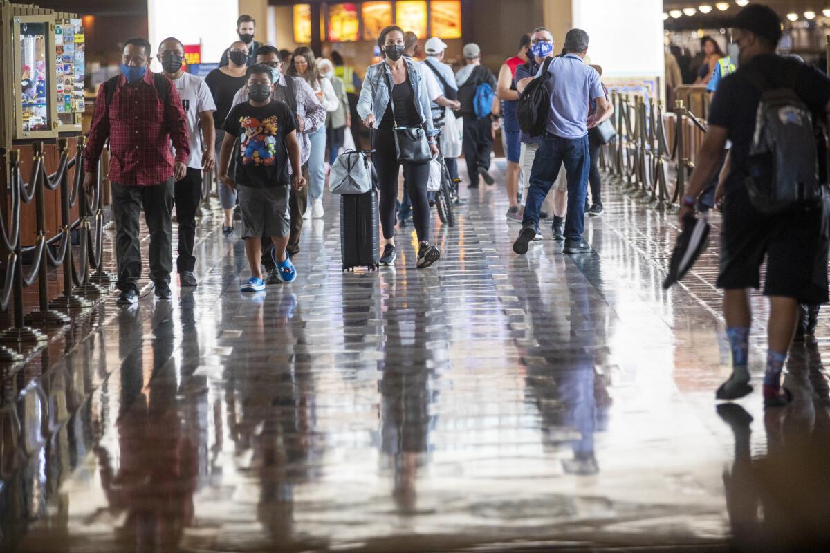 People with face masks walk through a great hall.