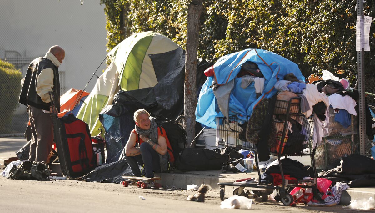 Homeless people outside their tents with their possessions on the street