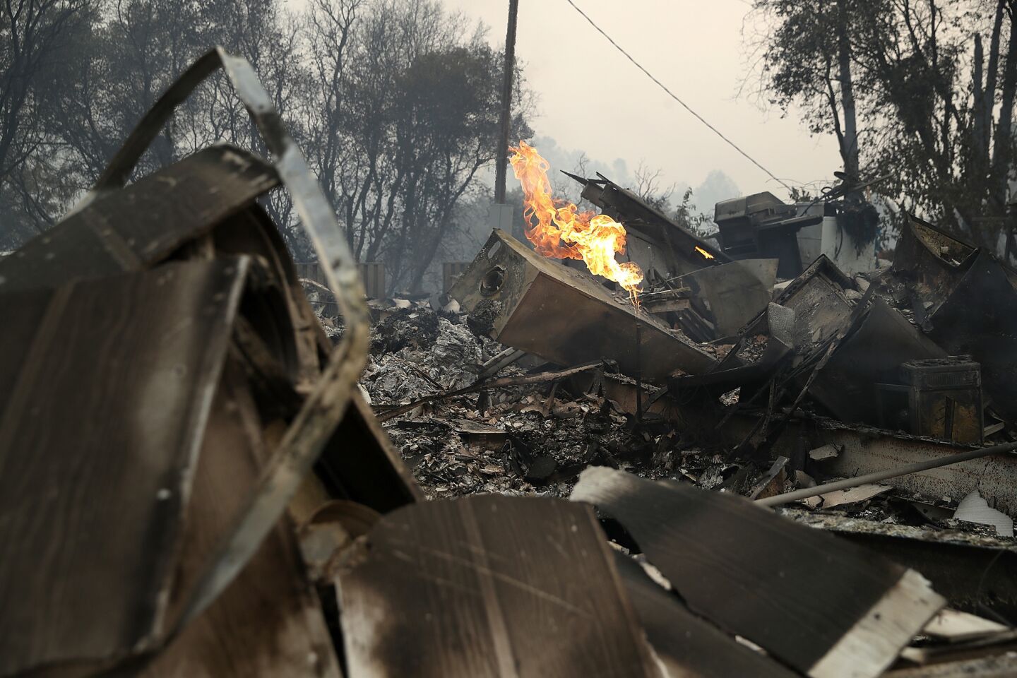 A gas line continues to burn at a home destroyed by the Detwiler fire in Mariposa, Calif.