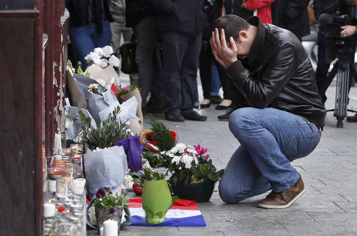 Un hombre llora frente a un monumento improvisado frente al café Carillon en París.