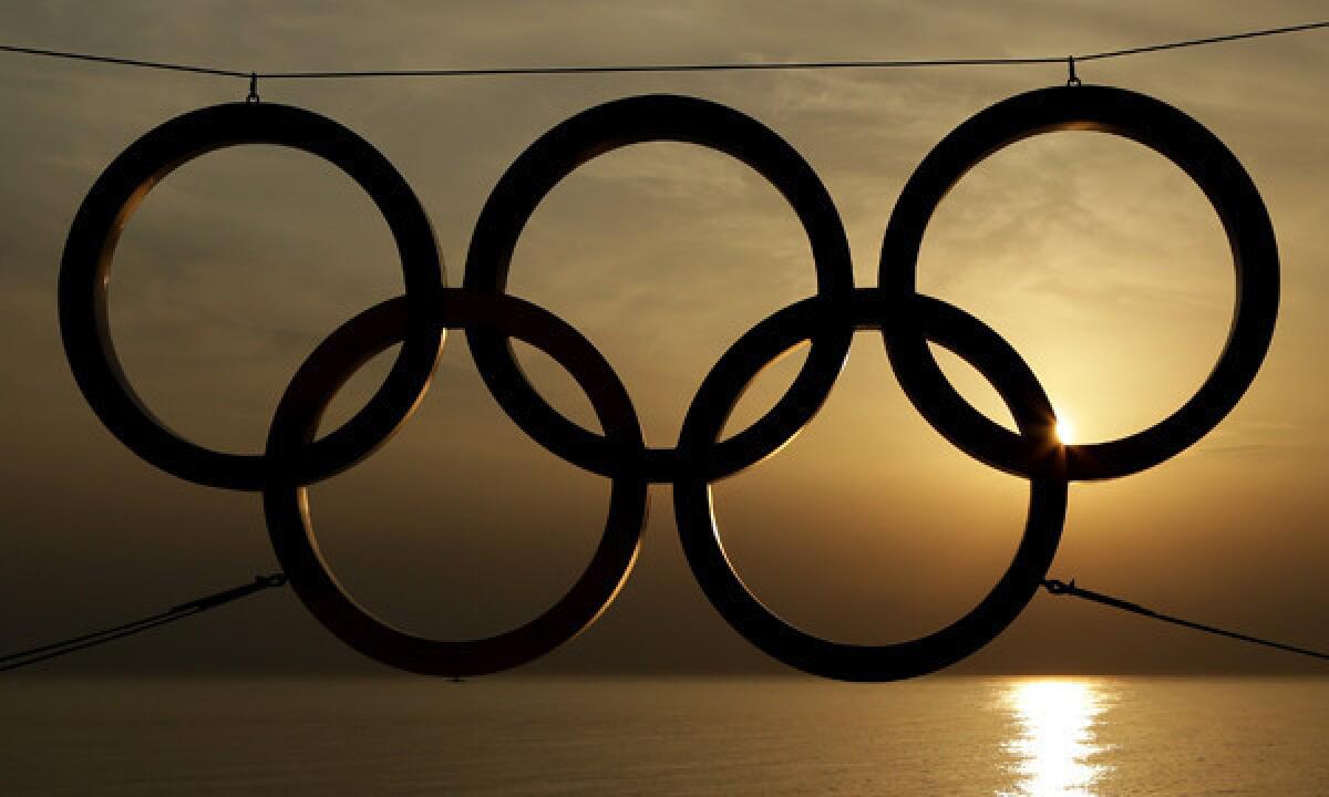 The sun sets on the Black Sea in Sochi, Russia, beyond an Olympic rings display.