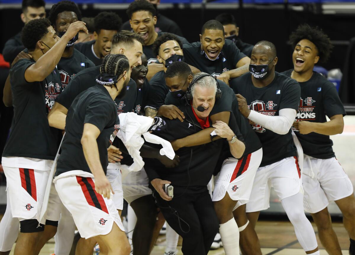 SDSU players surround coach Brian Dutcher after beating Utah State to win the Mountain West tournament last March.