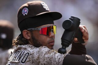 San Diego Padres' Luis Campusano uses a massage tool in the dugout during a baseball game against the Los Angeles Dodgers Sunday, Sept. 11, 2022, in San Diego. (AP Photo/Derrick Tuskan)