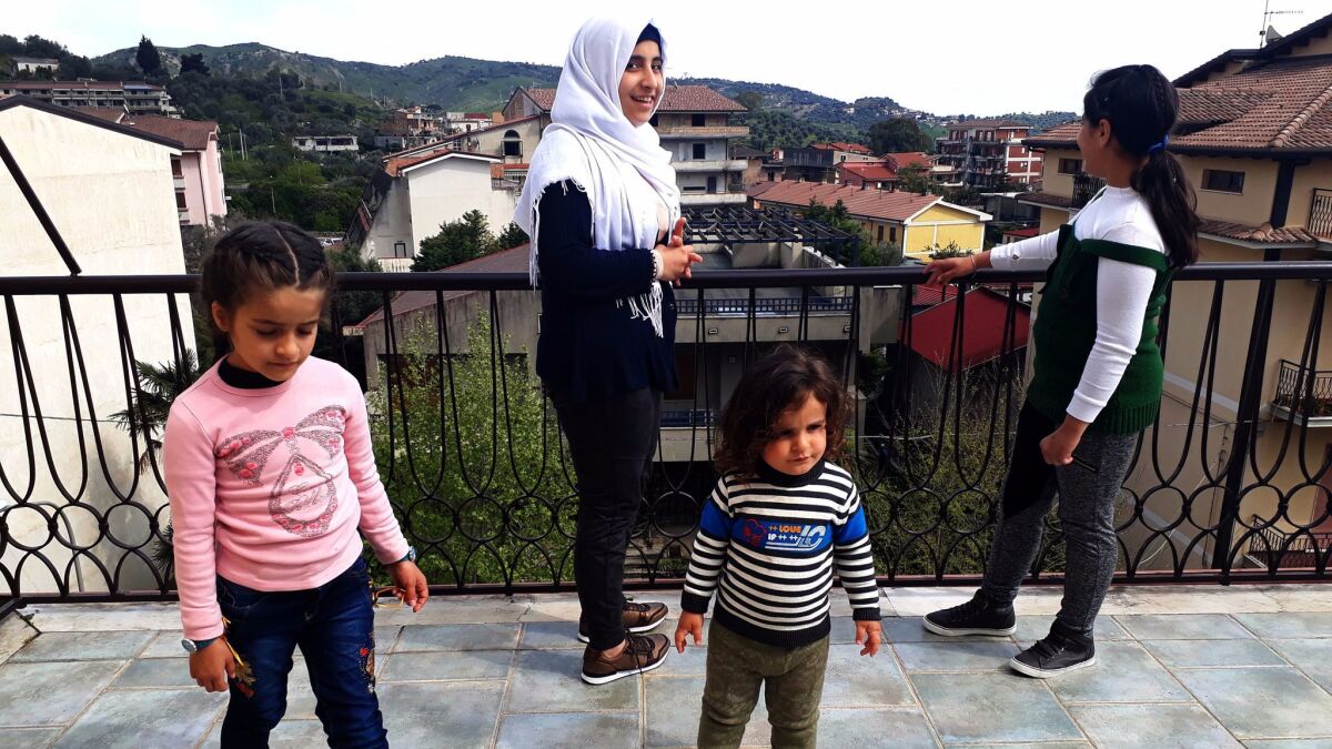 From left, Ghima, 7; Mais, 15; Bader, 2; and Ghazal, 11, stand on the rooftop terrace in their family's new home in the southern Italian town of Gioiosa Ionica.