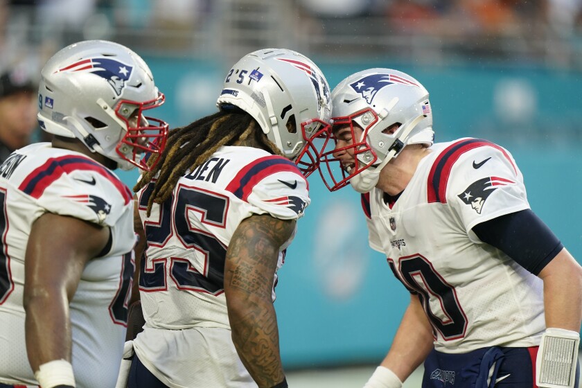 New England Patriots quarterback Mac Jones (10) celebrates with New England Patriots running back Brandon Bolden (25) after Bolden ran the ball in for a touchdown, during the first half of an NFL football game against the Miami Dolphins, Sunday, Jan. 9, 2022, in Miami Gardens, Fla. (AP Photo/Willfredo Lee)