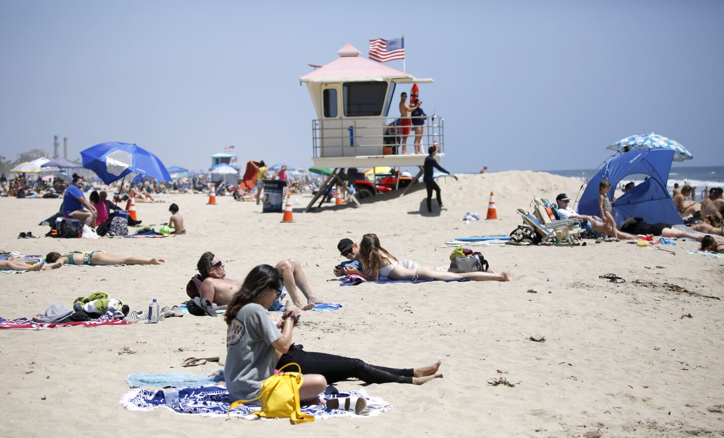 Beachgoers sunbathe near the Huntington Beach Pier on Saturday.