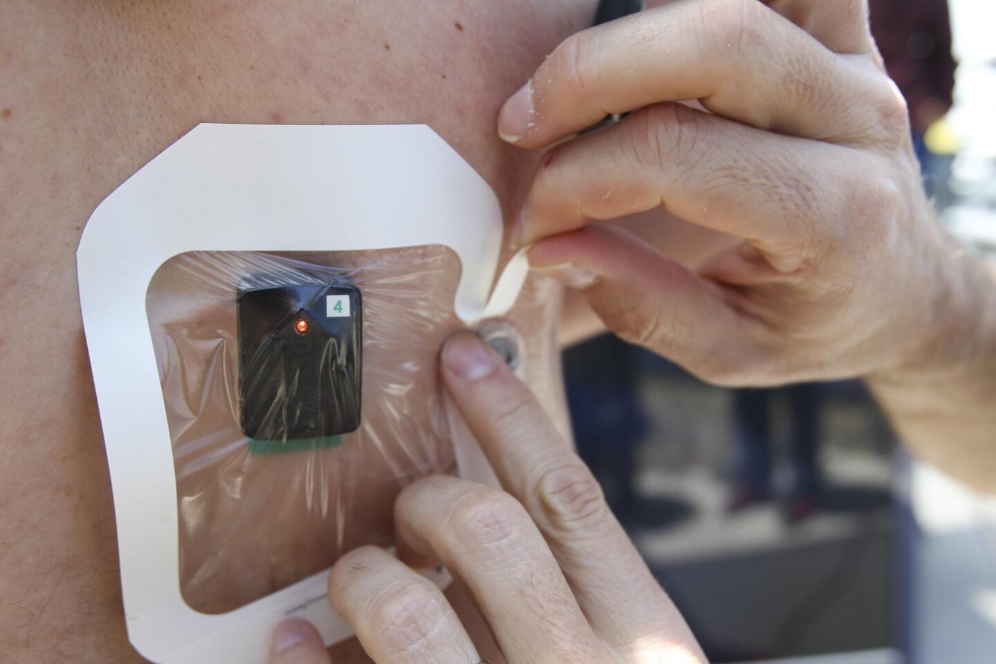 A waterproof bandage is placed over an EMG sensor, which measures muscle activity, as kinesiology student Cody Cuchna, 24, is prepped for a demonstration of how physical measurements are collected while paddling a surfboard in a swim flume.