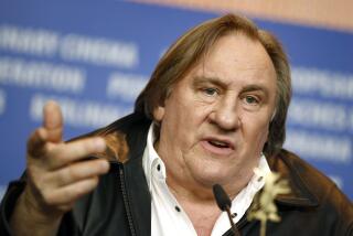 Actor Gerard Depardieu gestures with his hand behind a microphone
