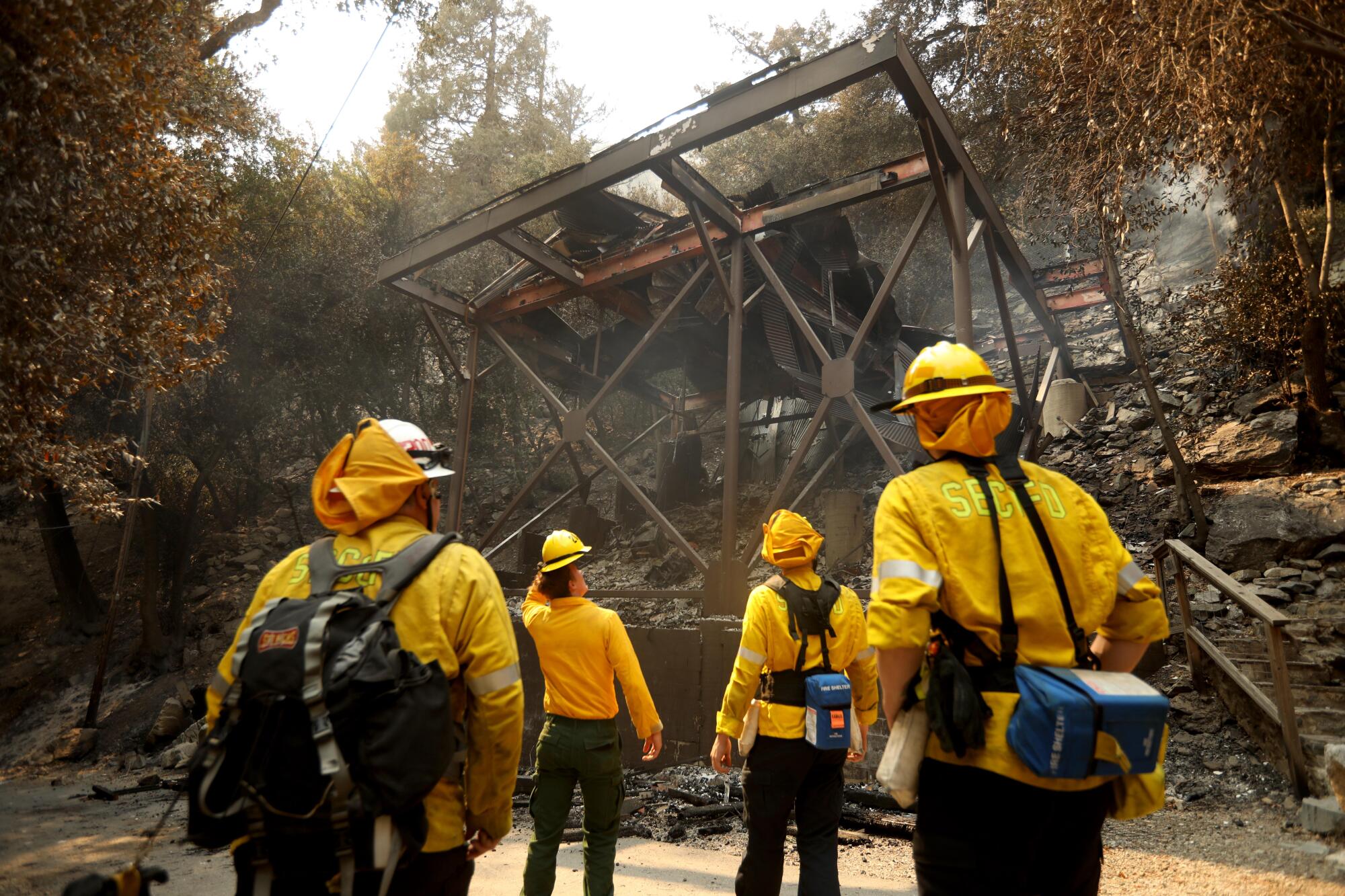 Mount Baldy Fire Department firefighters look over a home that was completely destroyed in the Bridge fire in Mount Baldy.