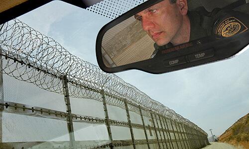 U.S. Border Patrol agent Richard Smith drives Wednesday along a section of the border fence in San Ysidro that was recently topped with razor wire.