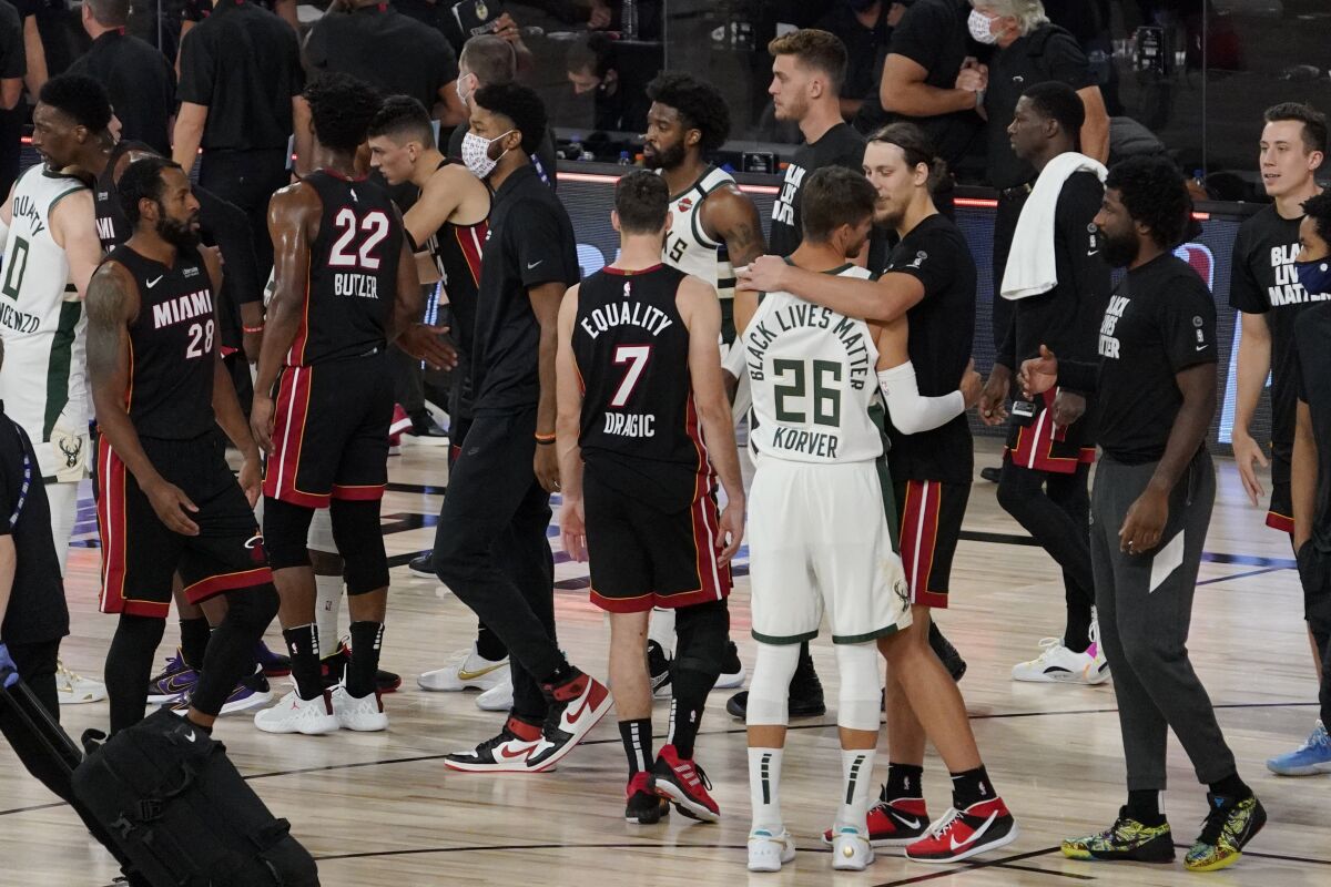 Miami Heat's Kelly Olynyk, right, and Milwaukee Bucks' Kyle Korver (26) embrace following their NBA conference semifinal playoff basketball game Tuesday, Sept. 8, 2020 in Lake Buena Vista, Fla. Miami won the game and eliminated the Bucks from the playoffs. (AP Photo/Mark J. Terrill)