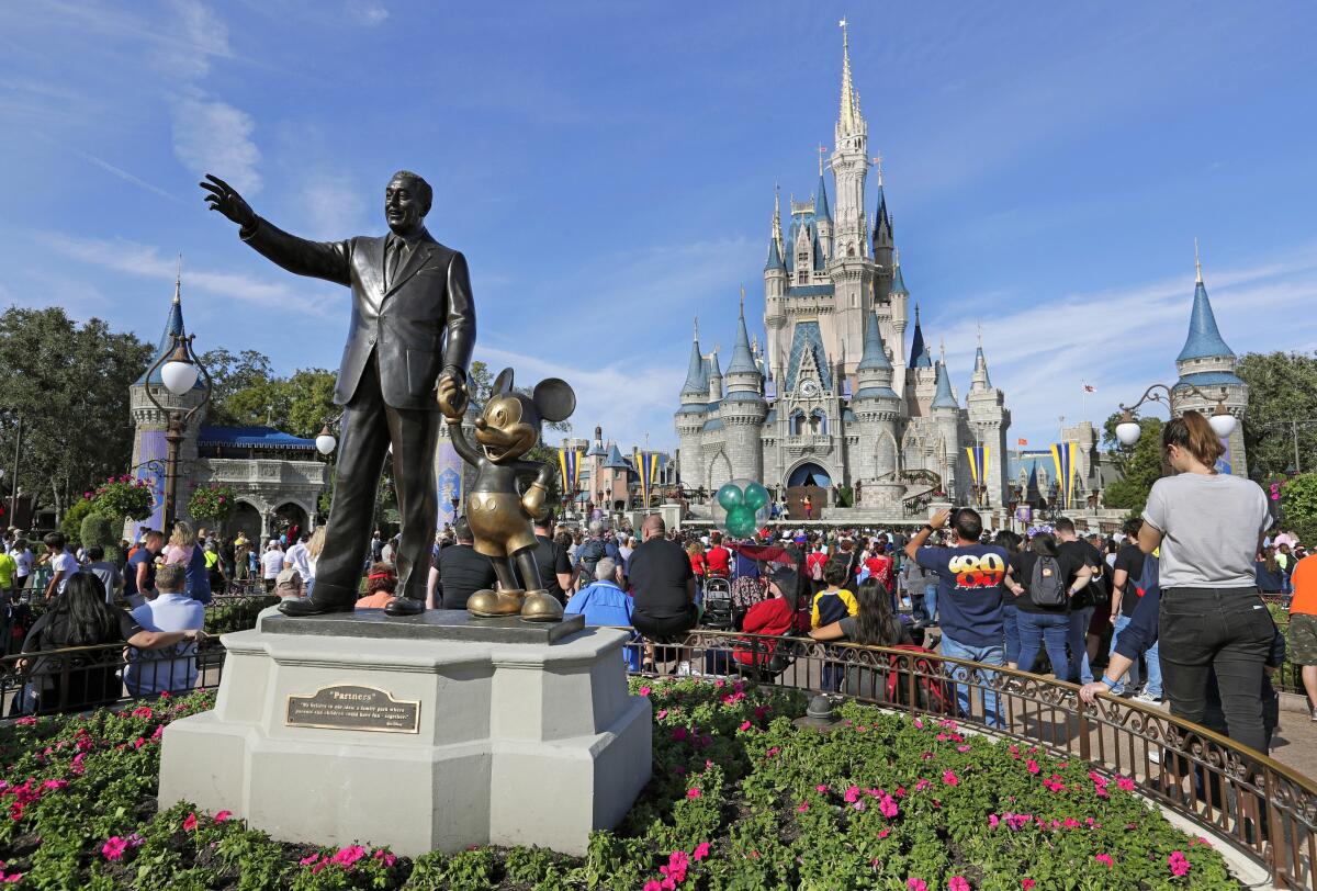 Guests watch a show near a statue of Walt Disney and Mickey Mouse