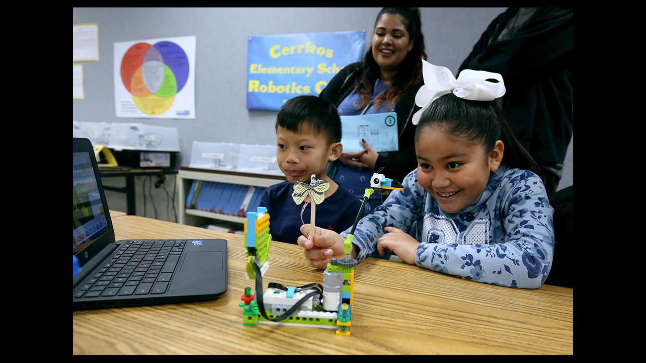 Cerritos Elementary School third graders Clive Vivero, left, and Katherine Altamira, right, show how a blocks bee moves around a blocks flower, connected via bluetooth to a computer, when given commands, during the Code To The Future Epic Showcase, at the school in Glendale on Thursday, Jan. 31, 2019.