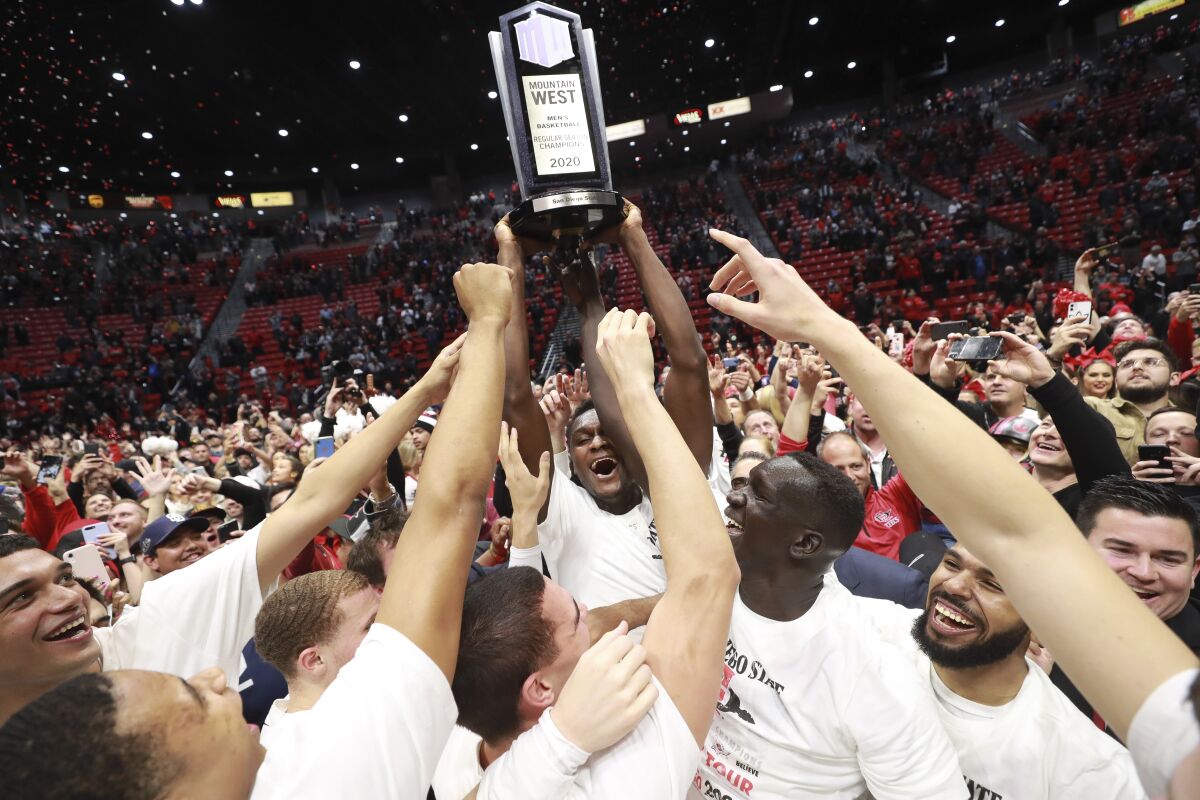 SDSU forward Joel Mensah holds up the Mountain West trophy as his celebrate after the Aztecs defeated New Mexico 82-59 at Viejas Arena on Feb. 11.