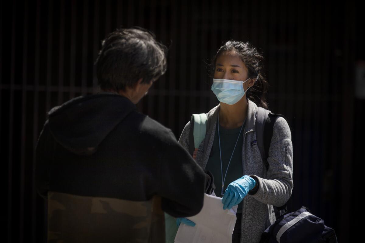 Nurse practitioner Jen King, right, speaks with a man living in an encampment on a Los Angeles sidewalk. "I feel like when you sign up for this job, you sign up to take certain risks and you have to treat people as safely as you can," she said.
