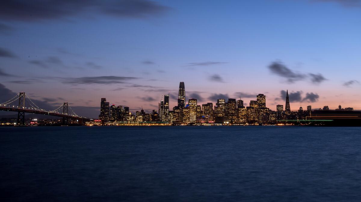 A large freight ship passes by the San Francisco skyline.