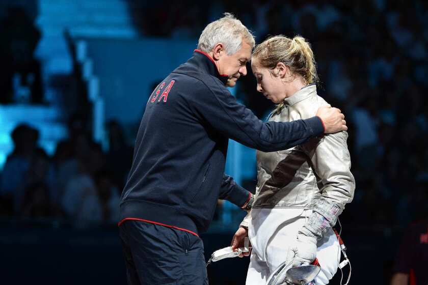 Mariel Zagunis of the United States is consoled by her coach after losing the bronze medal to Ukraine's Olga Kharlan in the women's sabre individual event.