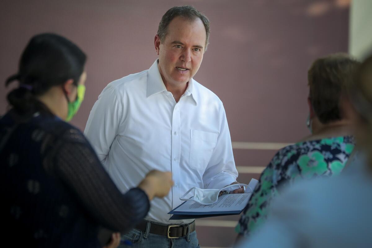 Adam Schiff holds a clipboard and speaks with women.