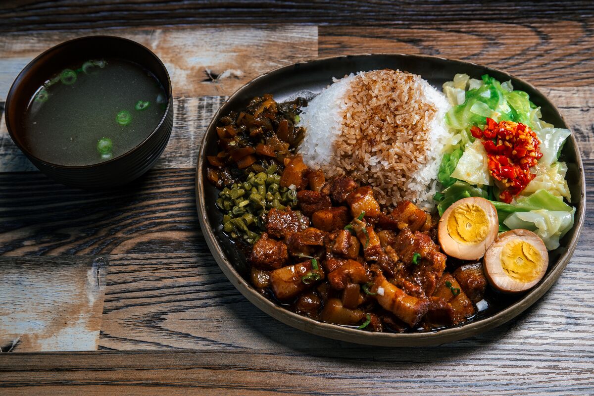 overhead view of braised pork with rice and chopped peppers and a hard-boiled egg