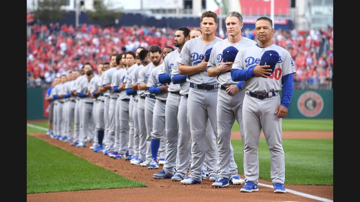 The Dodgers, including Manager Dave Roberts, stand for the national anthem before Game 1 of the NLDS on Friday at Nationals Park.
