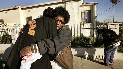 Annette Mackey, right, hugs Quiesha Orange near the site where three men were gunned down Monday evening, two of them fatally.